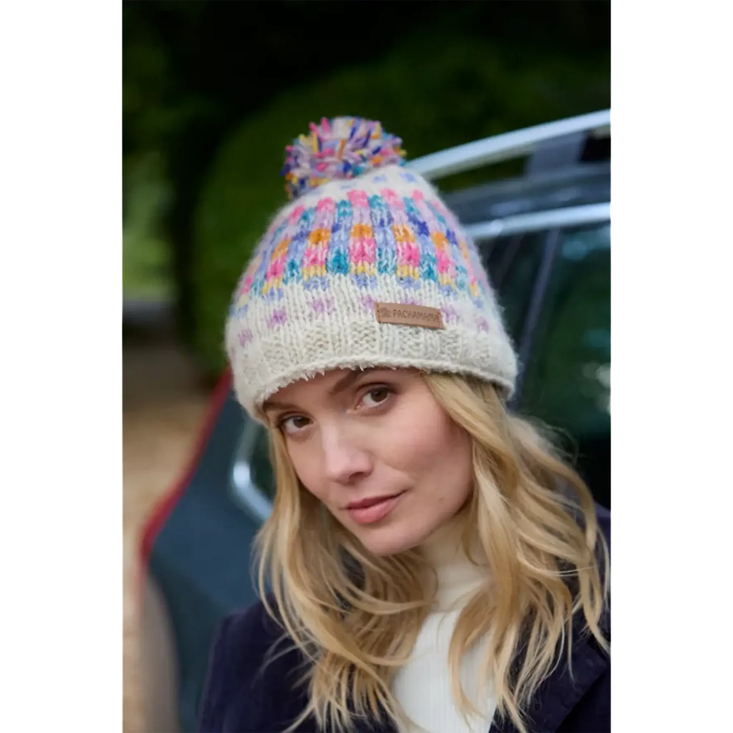 Model wearing oatmeal bobble hat with rainbow pastel check pattern