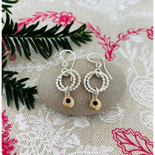 Silver earrings featuring two rings of circles and a dangling gold teardrops lifestyle image
