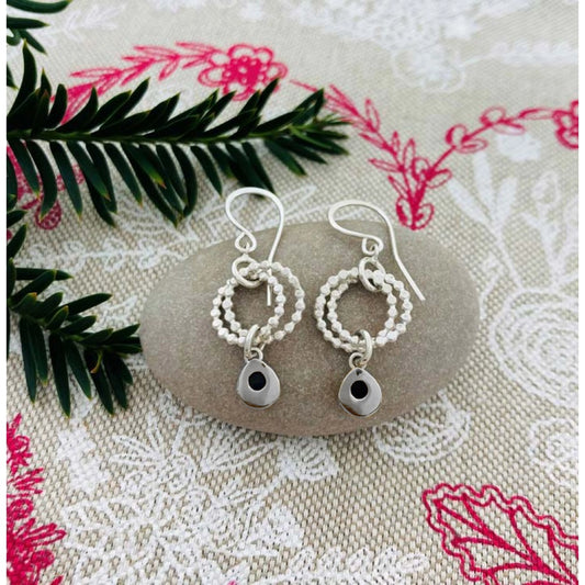 Silver earrings featuring two rings of circles and a dangling silver teardrops lifestyle image