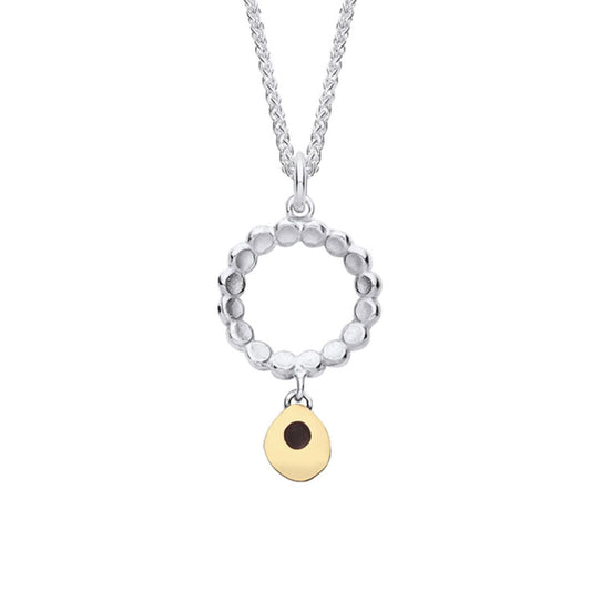 A silver pendant featuring a ring of little circles with a dangling gold droplet 