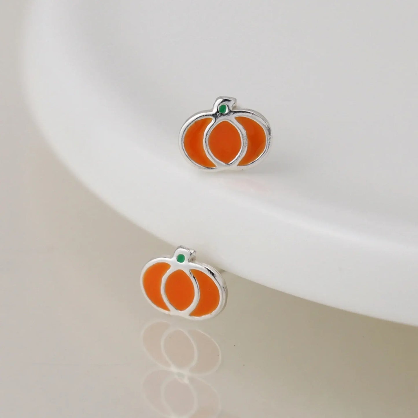 Pair of silver stud earrings shaped like pumpkins with enamelled details