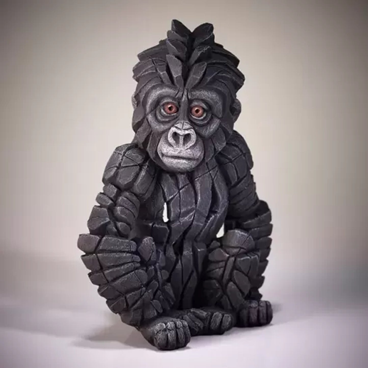 A textured and painted sitting baby gorilla sculpture