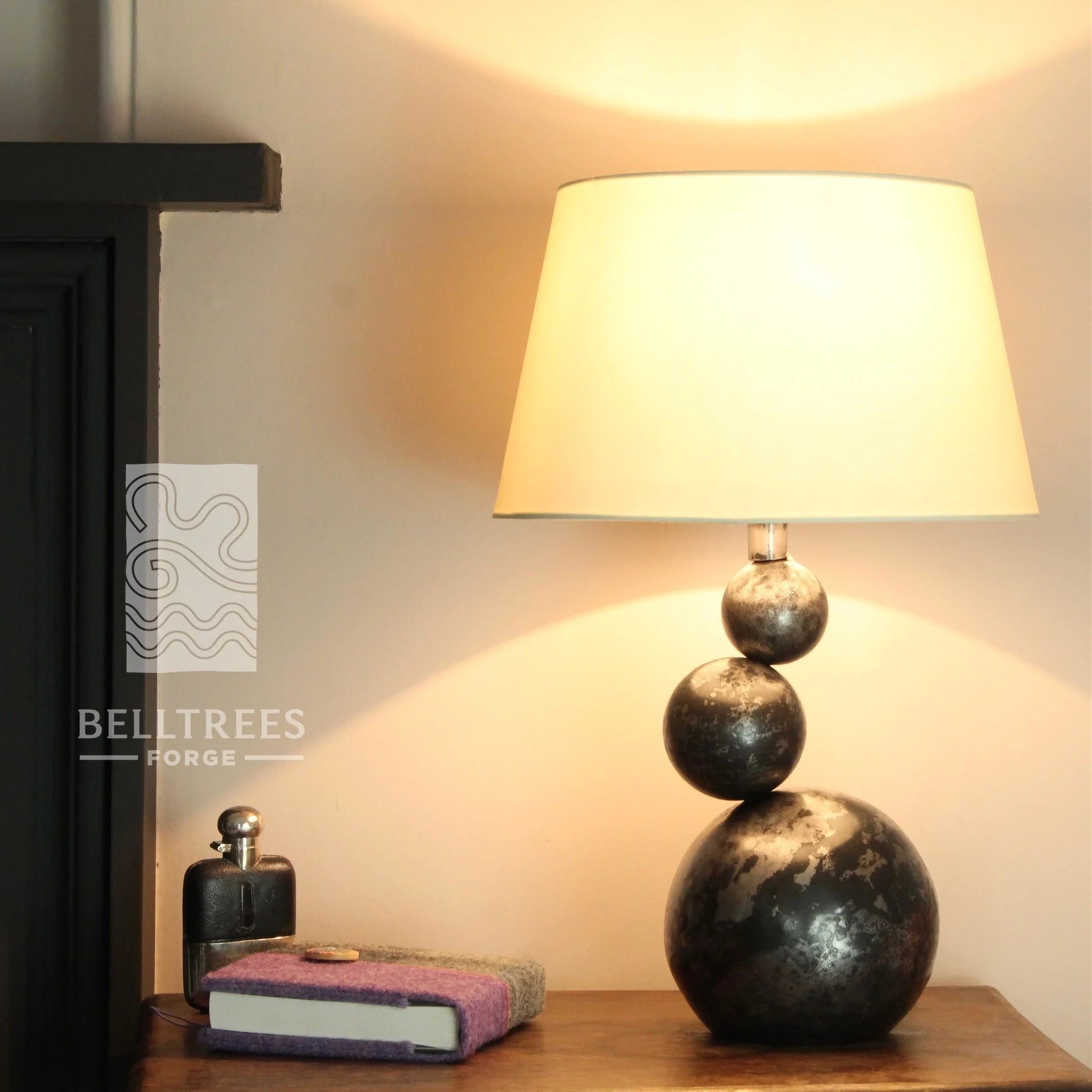 a steel table lamp with three balancing balls base and tilted drum shade