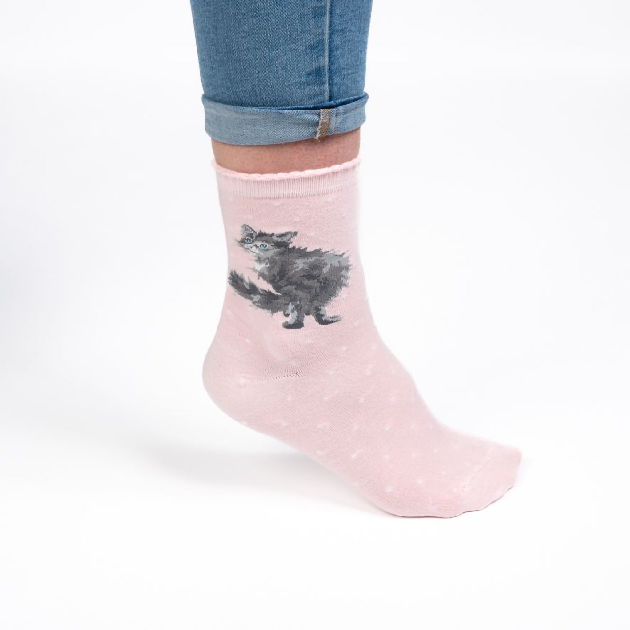Model wearing a pair of blush pink socks with a fluffy cat picture and white polka dots