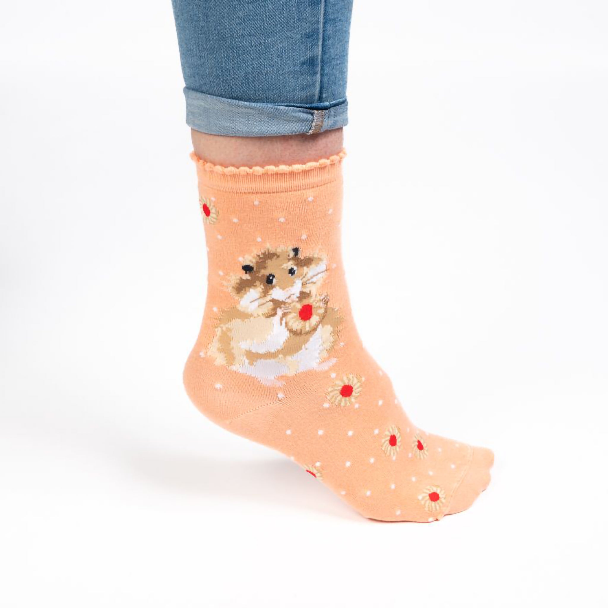Model wearing a pair of pink socks with a hamster and jam filled biscuits picture and white polka dots