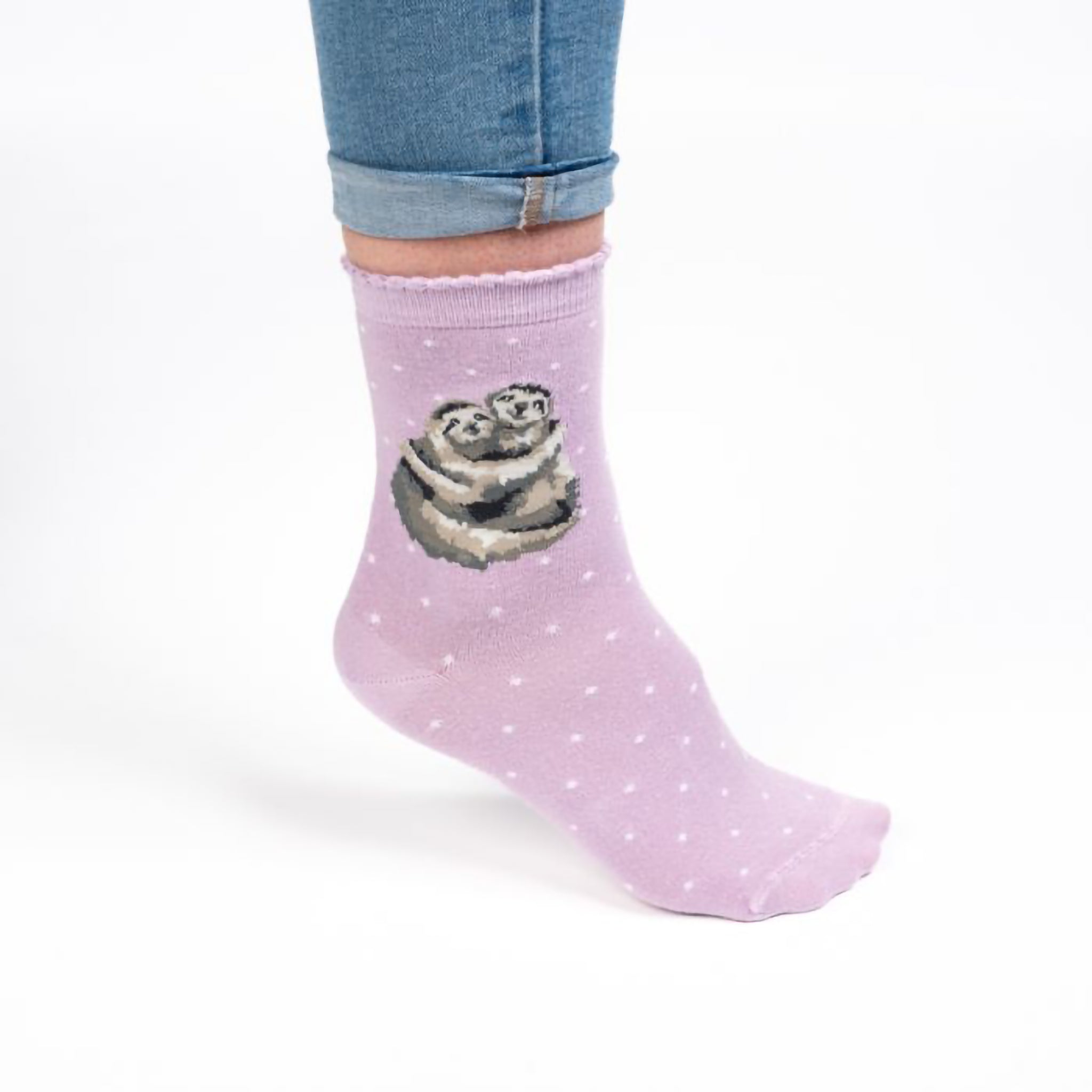 Model wearing a pair of purple socks with a picture of two cuddling sloths and white polka dots