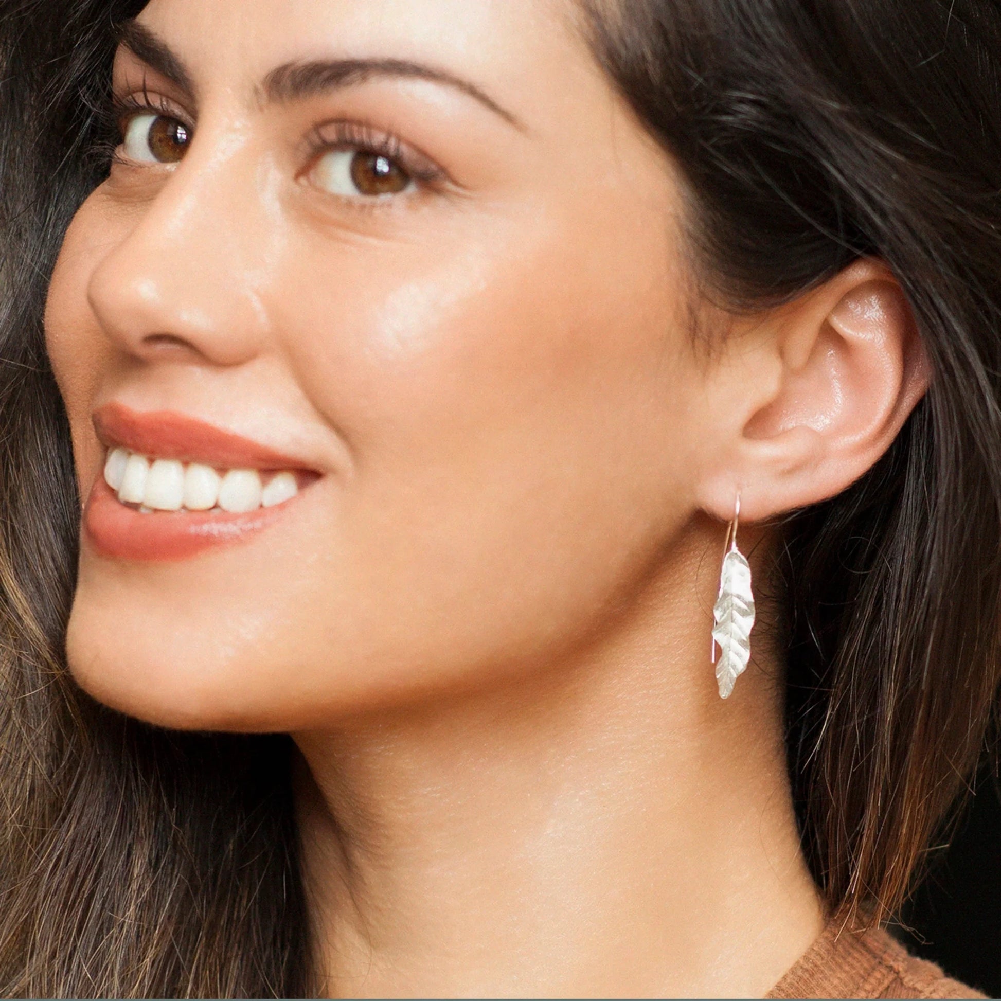 Model wearing silver satin banana leaf shaped threader earrings 