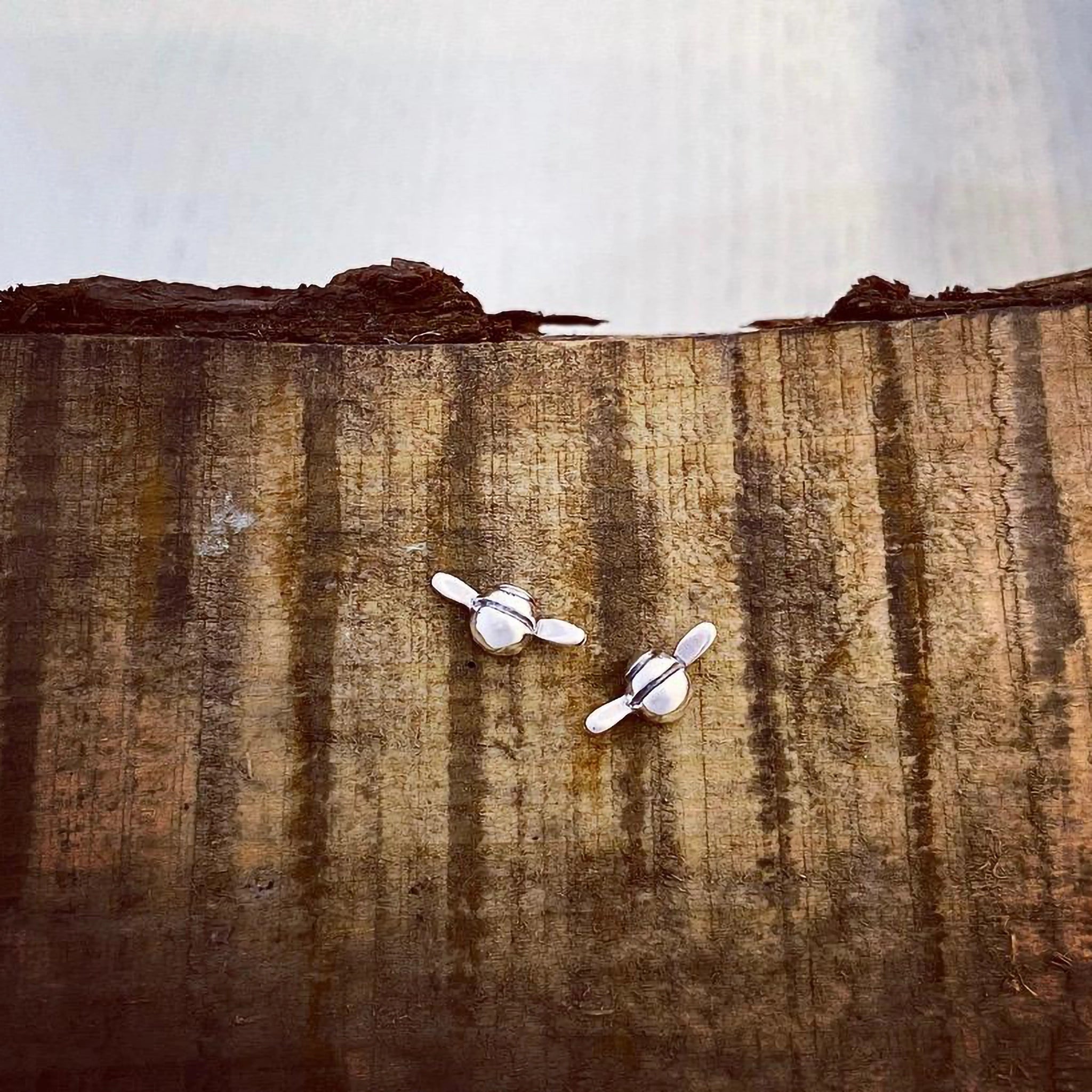 Silver stud earrings shaped like little flying bees