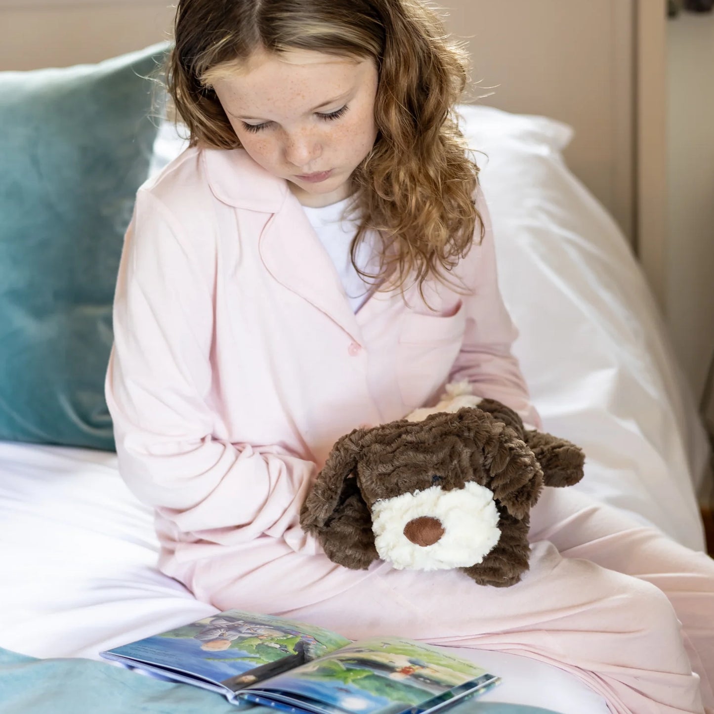 Child cuddling plush brown dog toy with microwavable flax-seed head bag insert