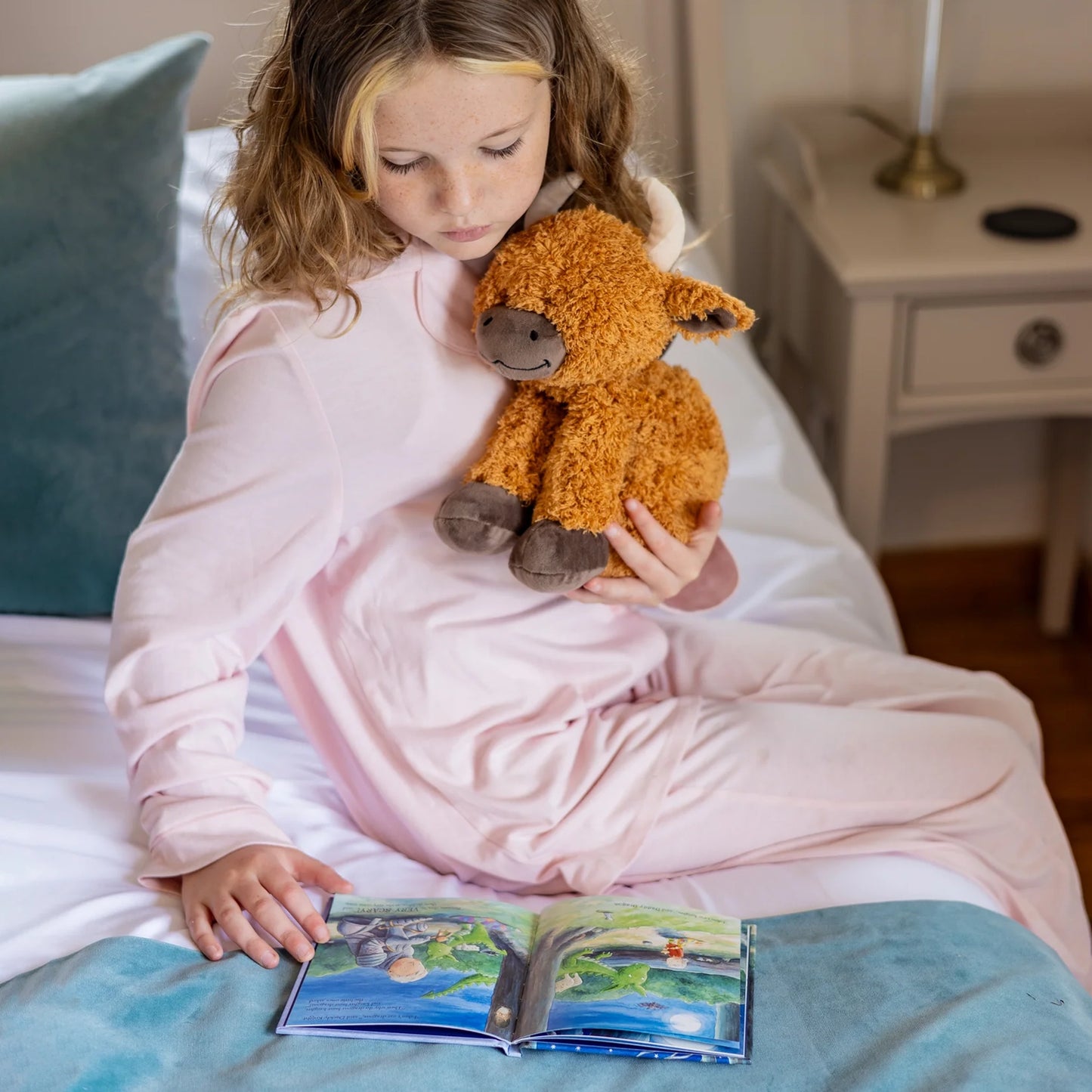 Child cuddling plush Highland cow toy with microwavable flax-seed head bag insert