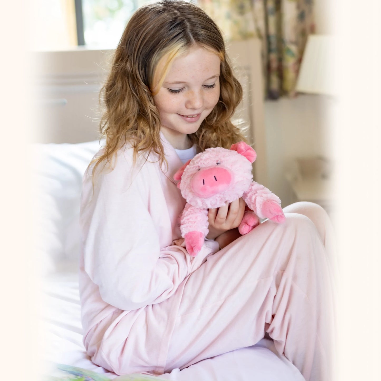 Child cuddling plush pink pig toy with microwavable flax-seed head bag insert