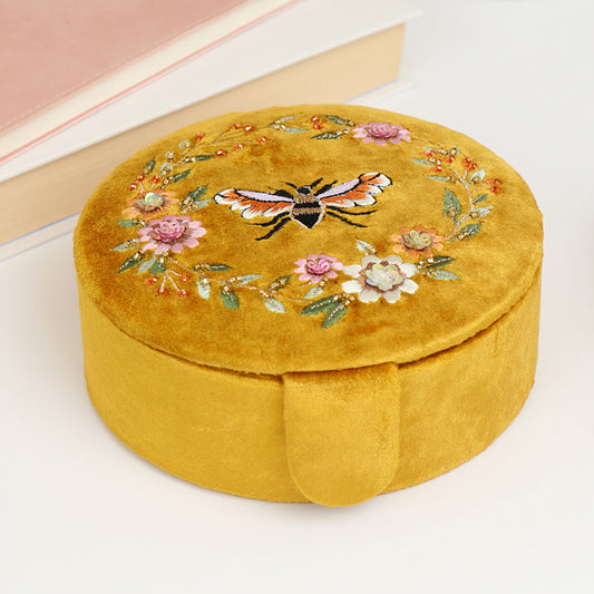 A mustard yellow velvet round jewellery box with embroidered bee and flowers