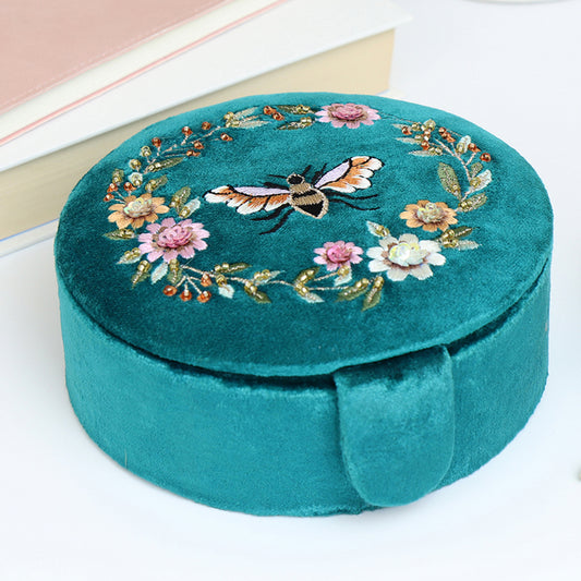 A teal blue velvet round jewellery box with embroidered bee and flowers