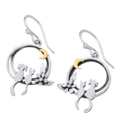 A pair of silver earrings featuring a cat and dog sat together under a gold moon