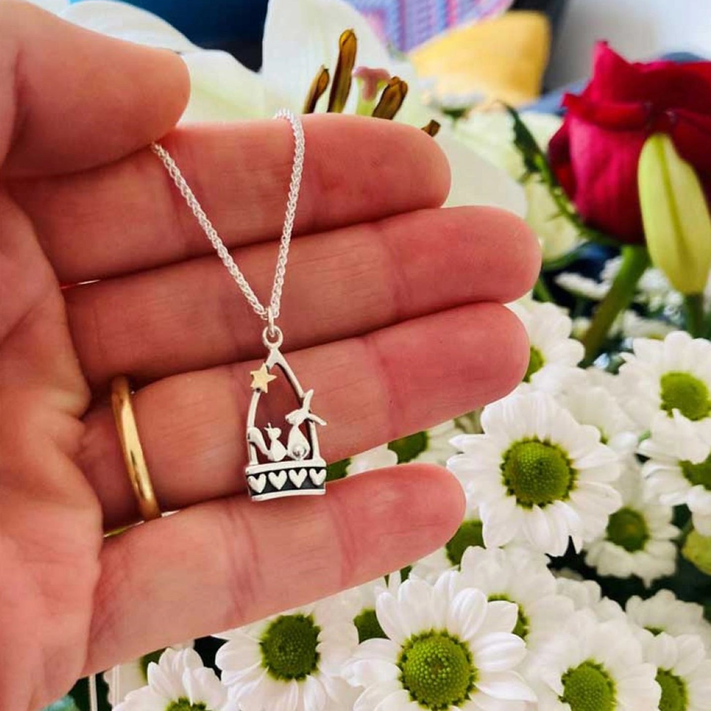 A silver stirrup pendant with a little hare and squirrel, heart details and a gold star lifestyle
