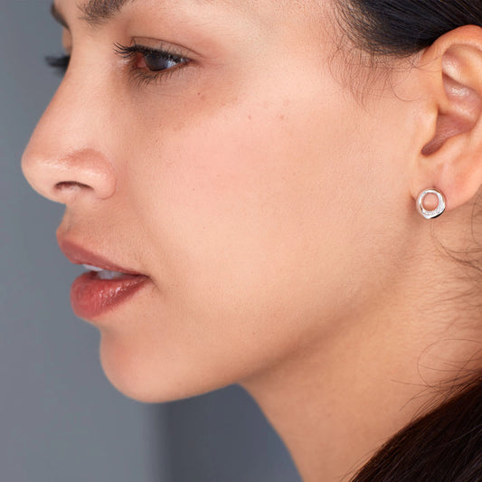 Model wearing a pair of open bevel circle silver studs with cubic zirconia