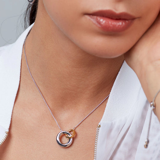 Model wearing a necklace with linked silver and gold rings with bevel shape