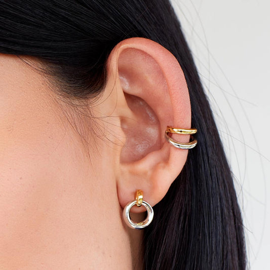 Model wearing a pair of silver loop drop earrings with gold loop bails
