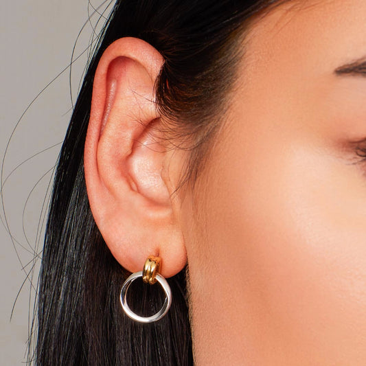 Model wearing a pair of silver loop drop earrings with double gold loop bails