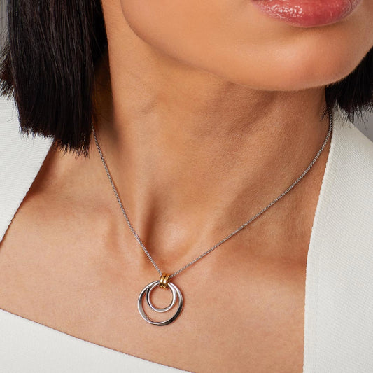 Model wearing silver pendant featuring two golden hoops with two silver loops threaded through