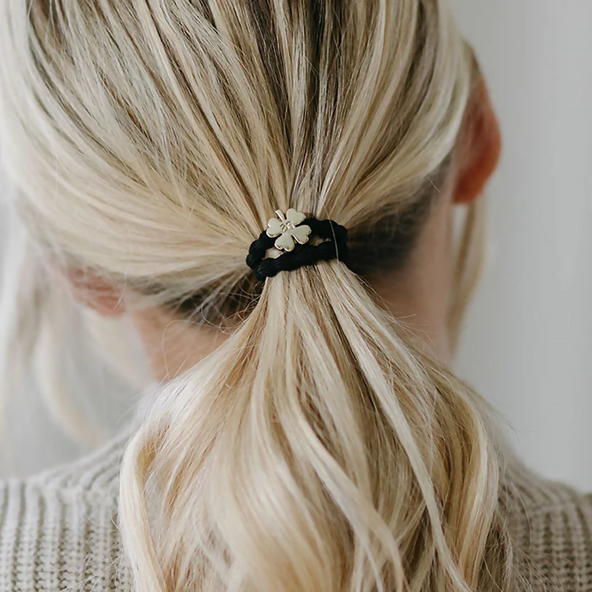 Model wearing elastic bubble hair band in black with gold clover charm