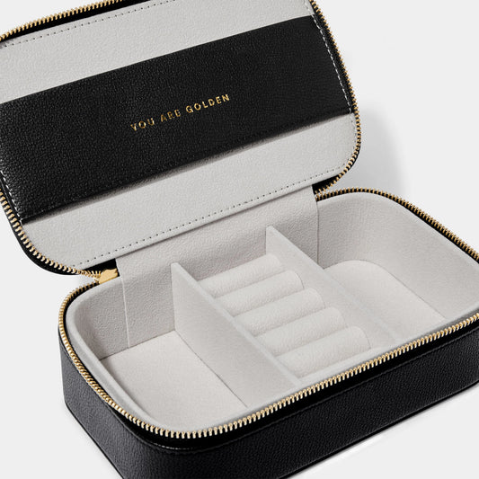 A small open jewellery box in black with grey interior with three compartments and a phrase in gold lettering