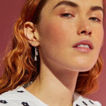 Model wearing satin silver drop earrings with two dangly bluebell flowers