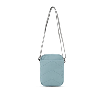 A small crossbody bag in canvas material and a light blue colour back