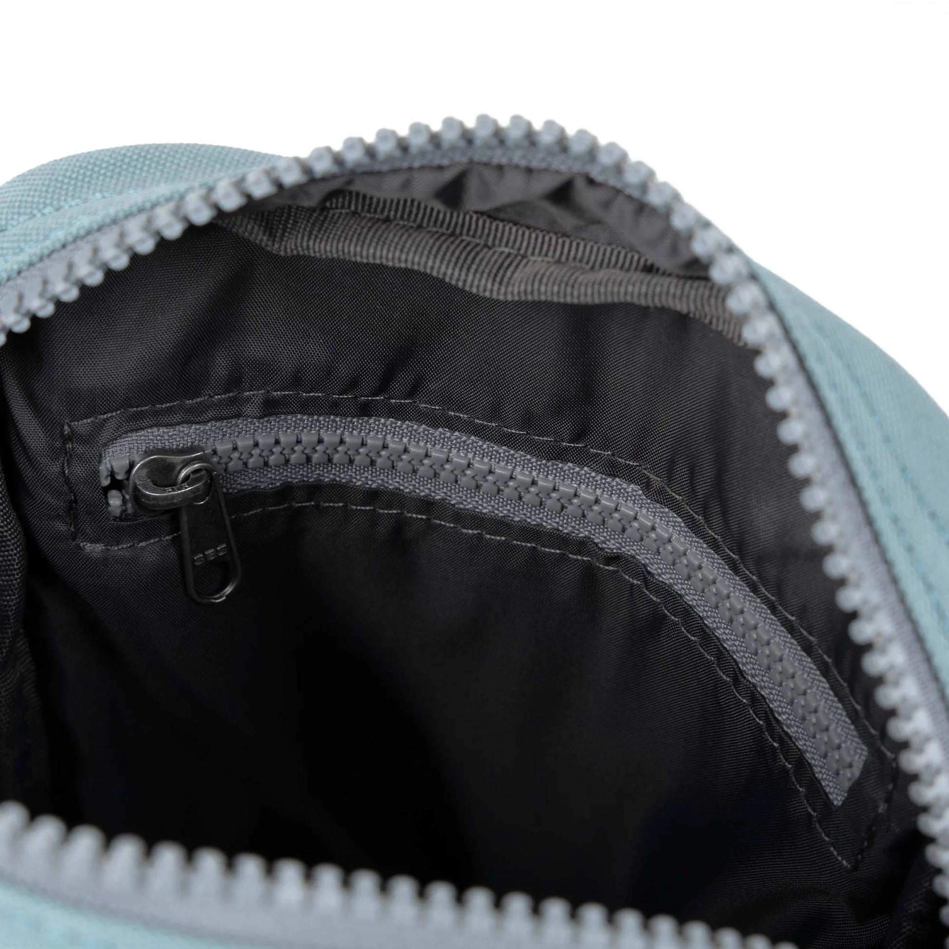 A small crossbody bag in canvas material and a light blue colour open