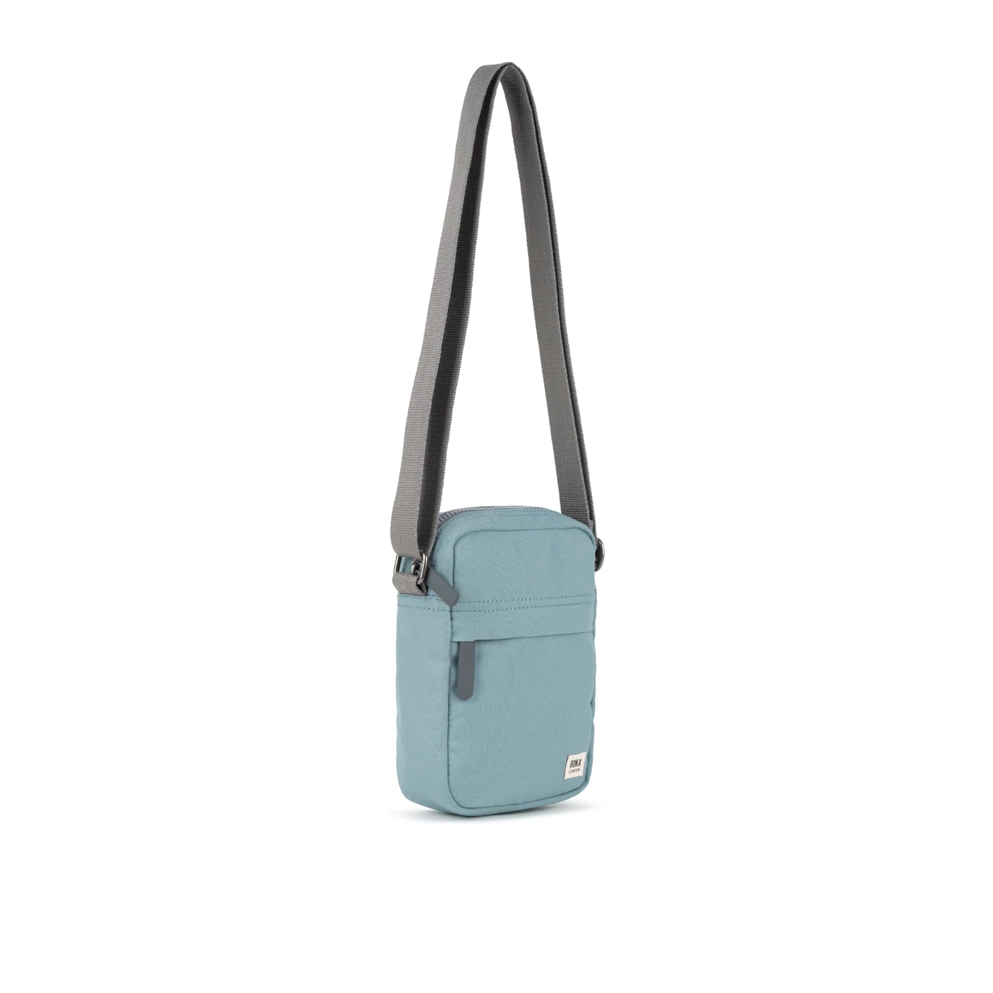 A small crossbody bag in canvas material and a light blue colour side view