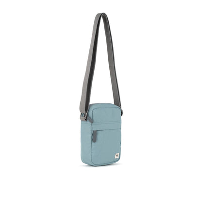 A small crossbody bag in canvas material and a light blue colour side view