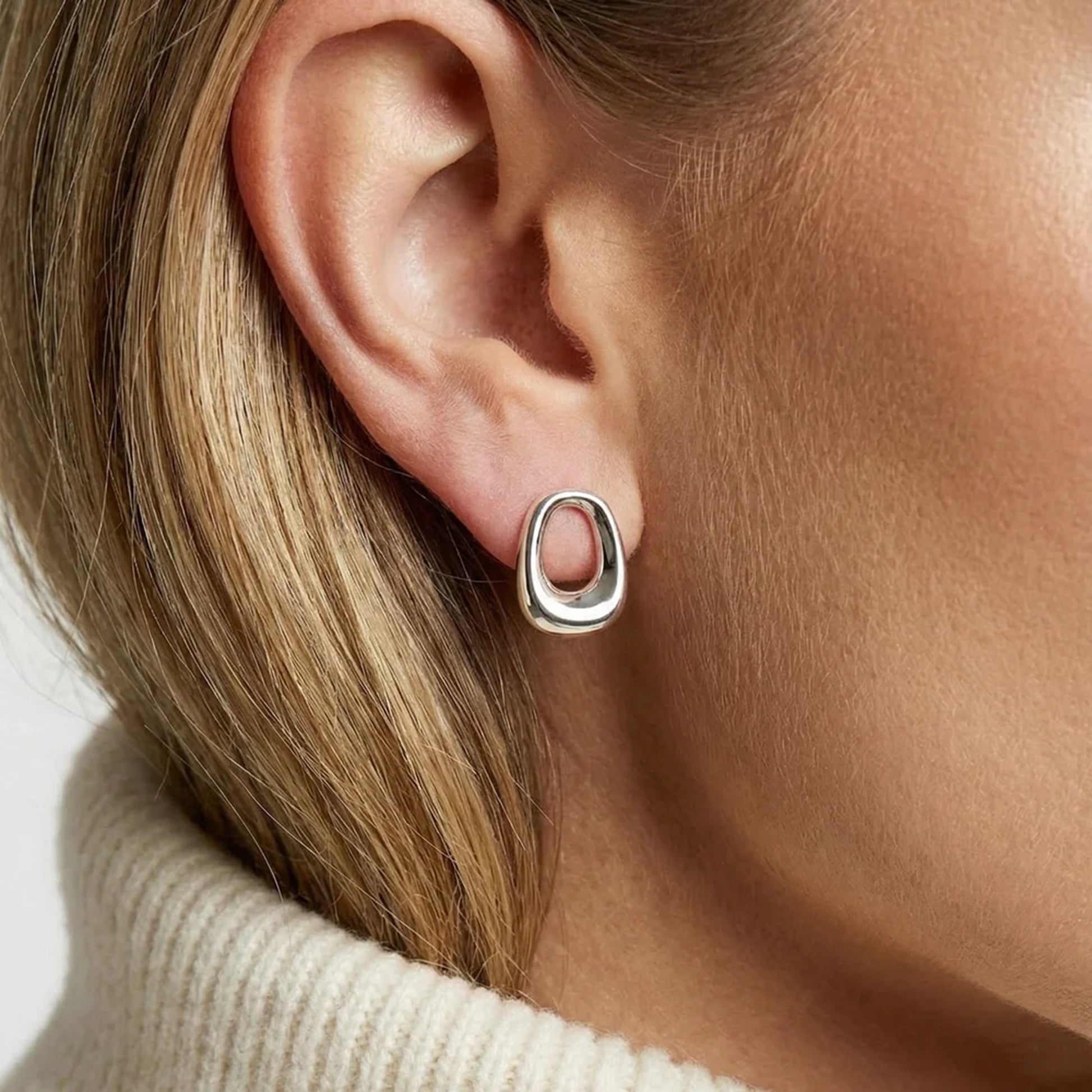 Model wearing modern design silver curved rectangular stud earrings with open centres