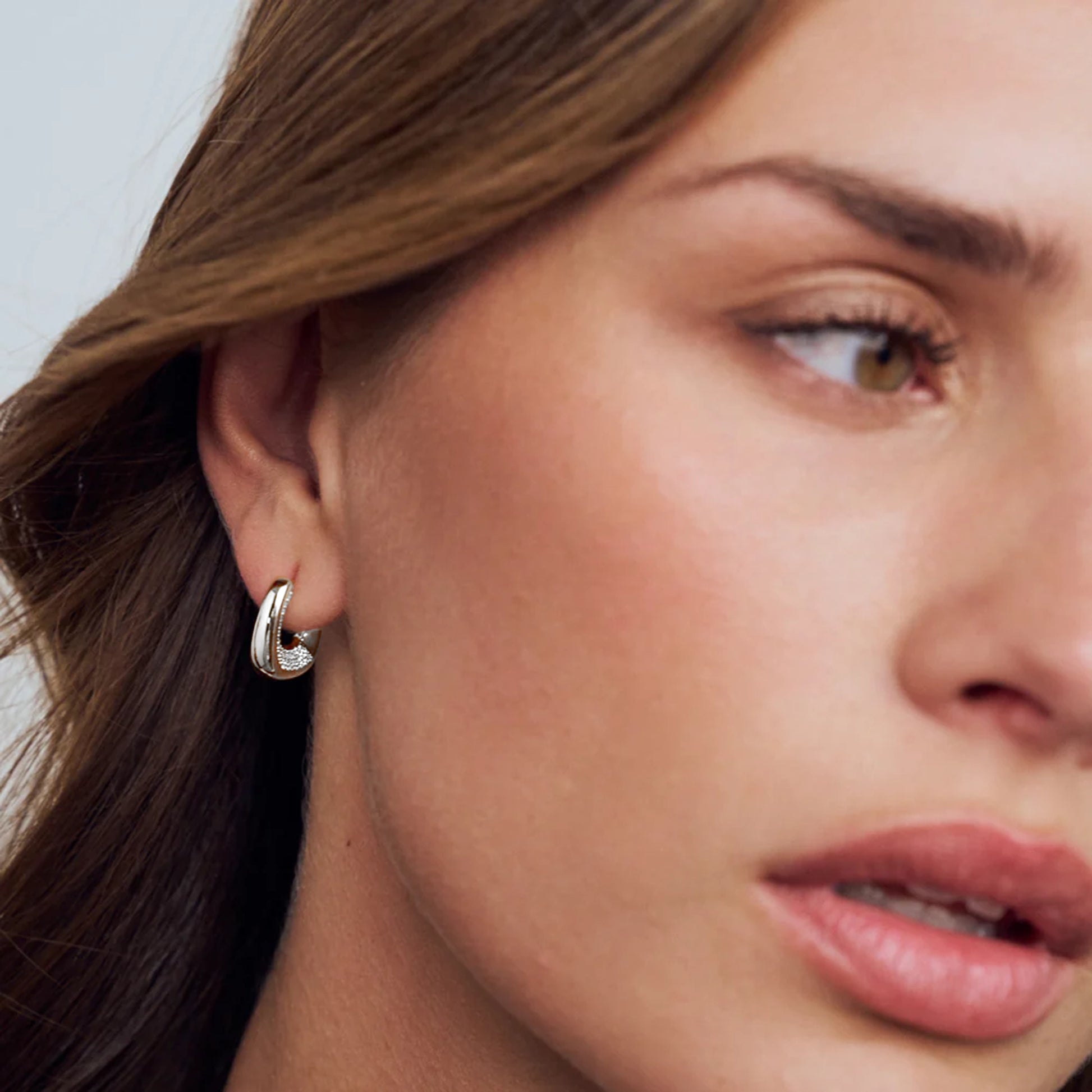 Model wearing open curved rectangle silver hoop earrings with CZ pave in the opening