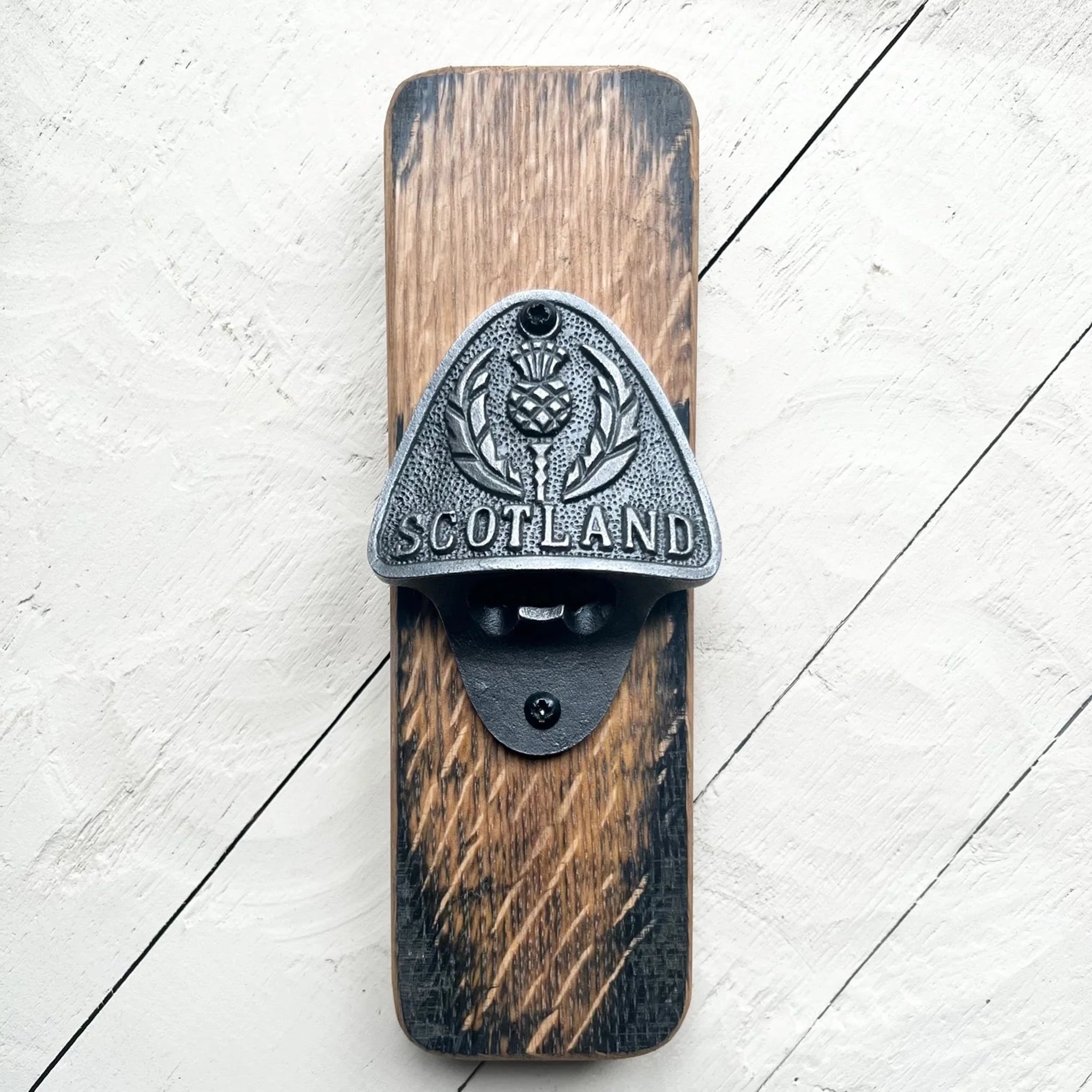 A whisky barrel bottle opener with metal detail featuring thistle and 'Scotland'