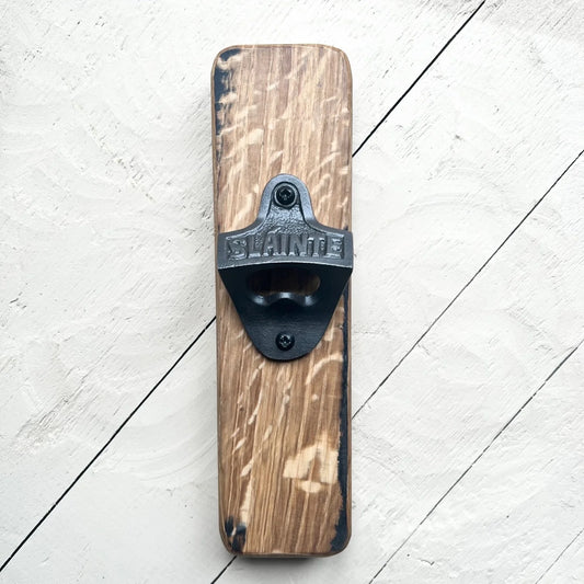 A whisky barrel bottle opener with metal detail featuring thistle and 'Sláinte''