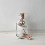 A small cork stopped glass bottle with dried flowers inside and a label that reads 'lovely mum'