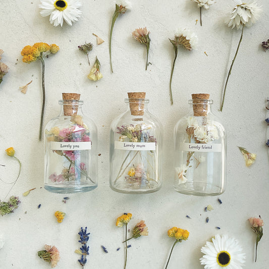 A set of small cork stopped glass bottles with little labels and dried flowers