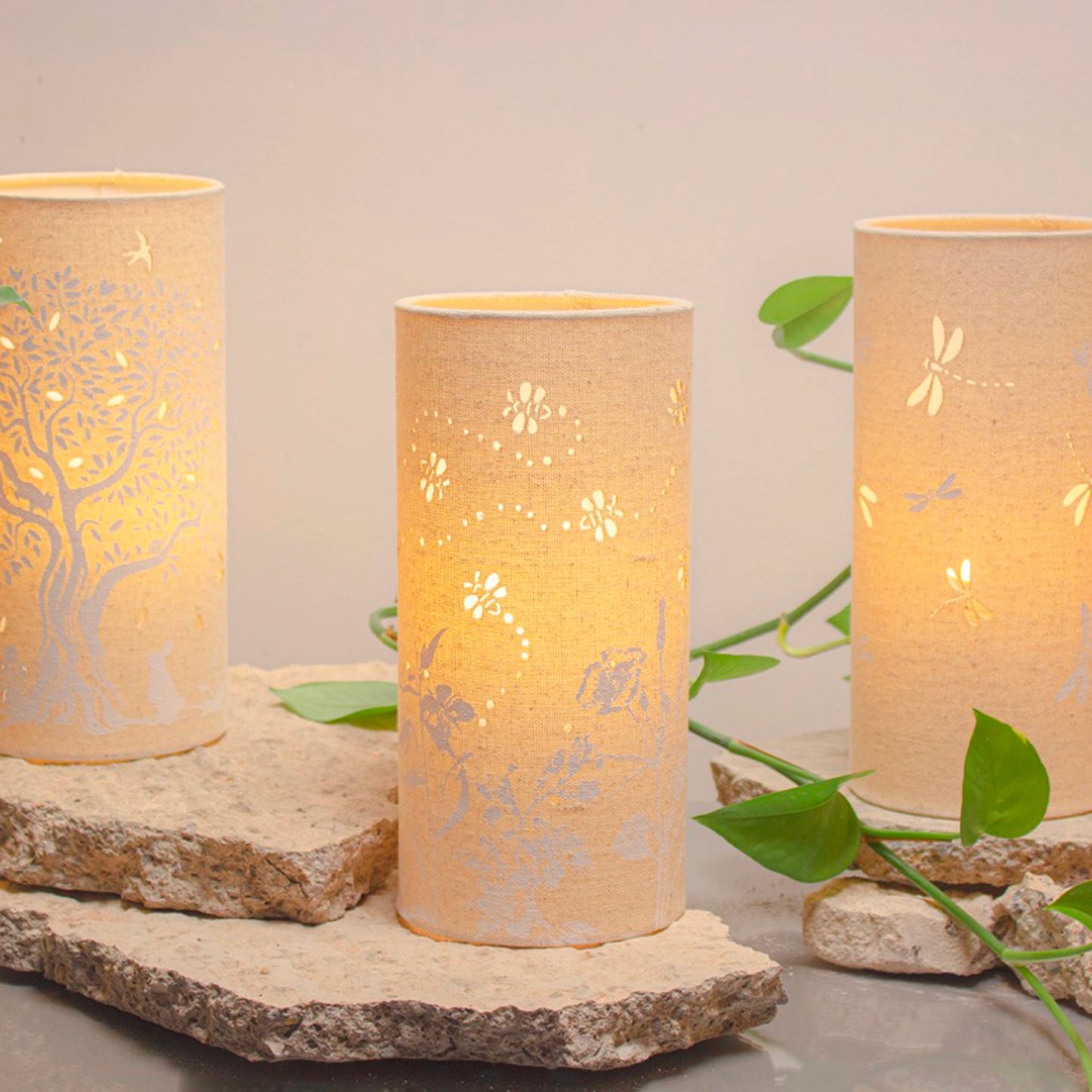 A linen look fabric table lamp with a flower and bumblebee design and cut out leaf details lifestyle