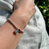 Model wearing a silver beaded bracelet with a blue enamel butterfly pendant