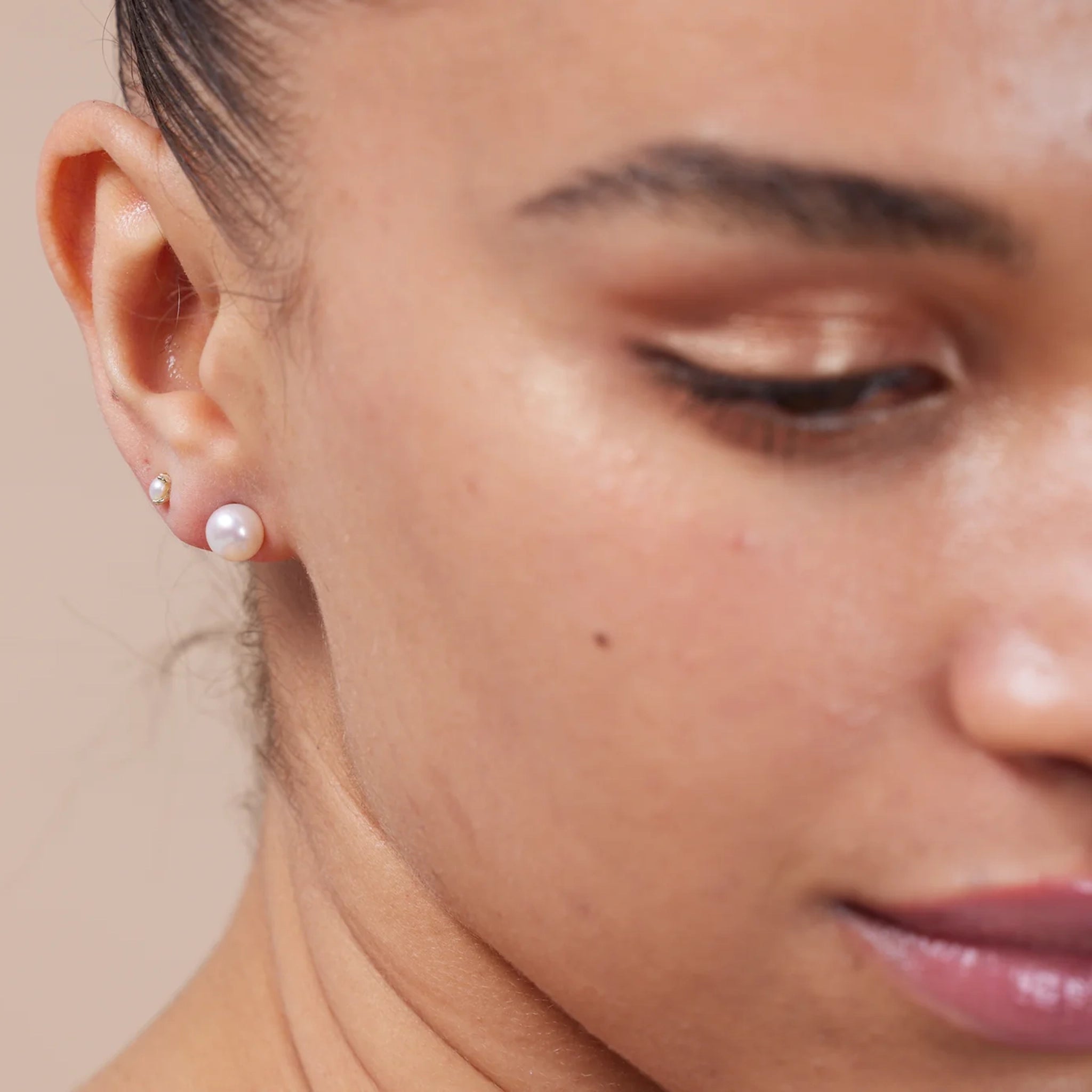 Model wearing simple round button shaped white pearl stud earrings