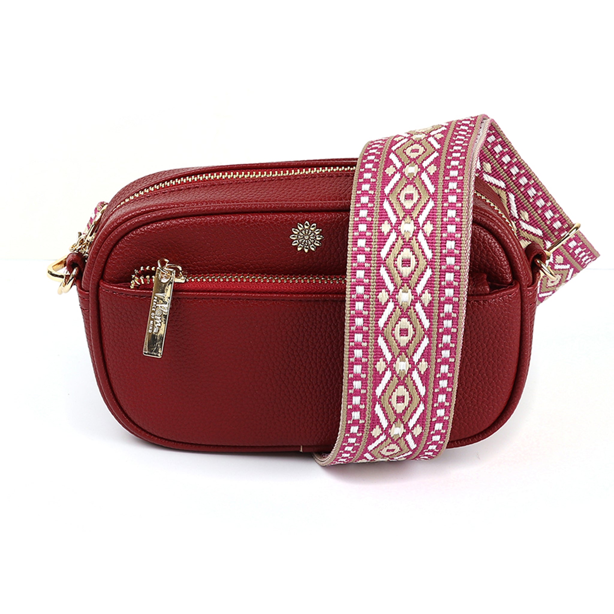 A vegan leather camera bag in bright red with gold hardware an woven diamond patterned pink and gold strap