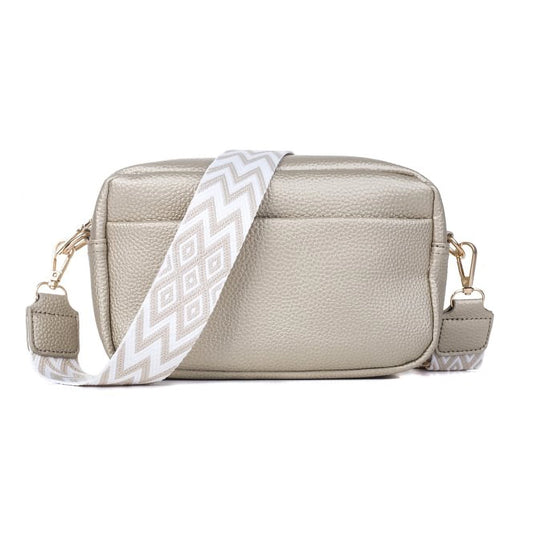 A camera bag in a metallic gold colour with a woven geometric strap in beige and white