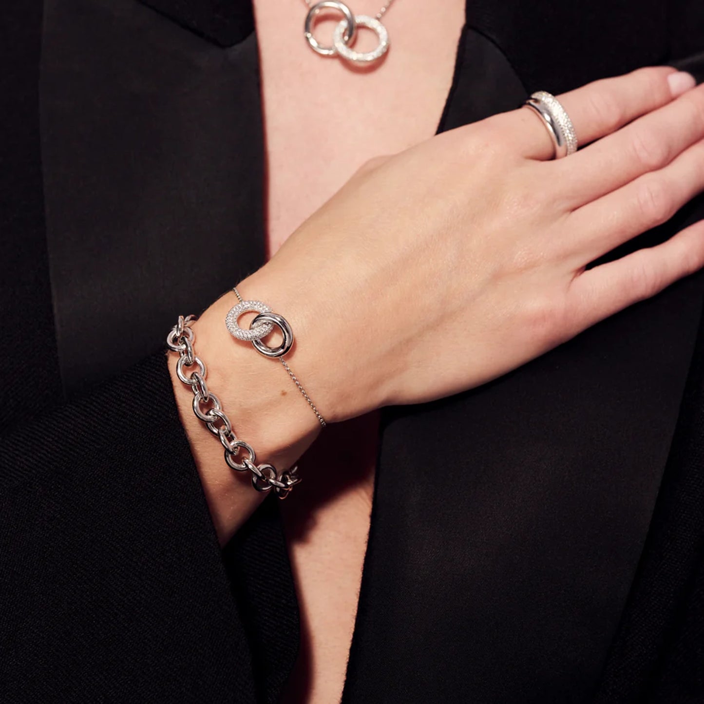 Model wearing silver bracelet with two interlocking rings, one with CZ stones