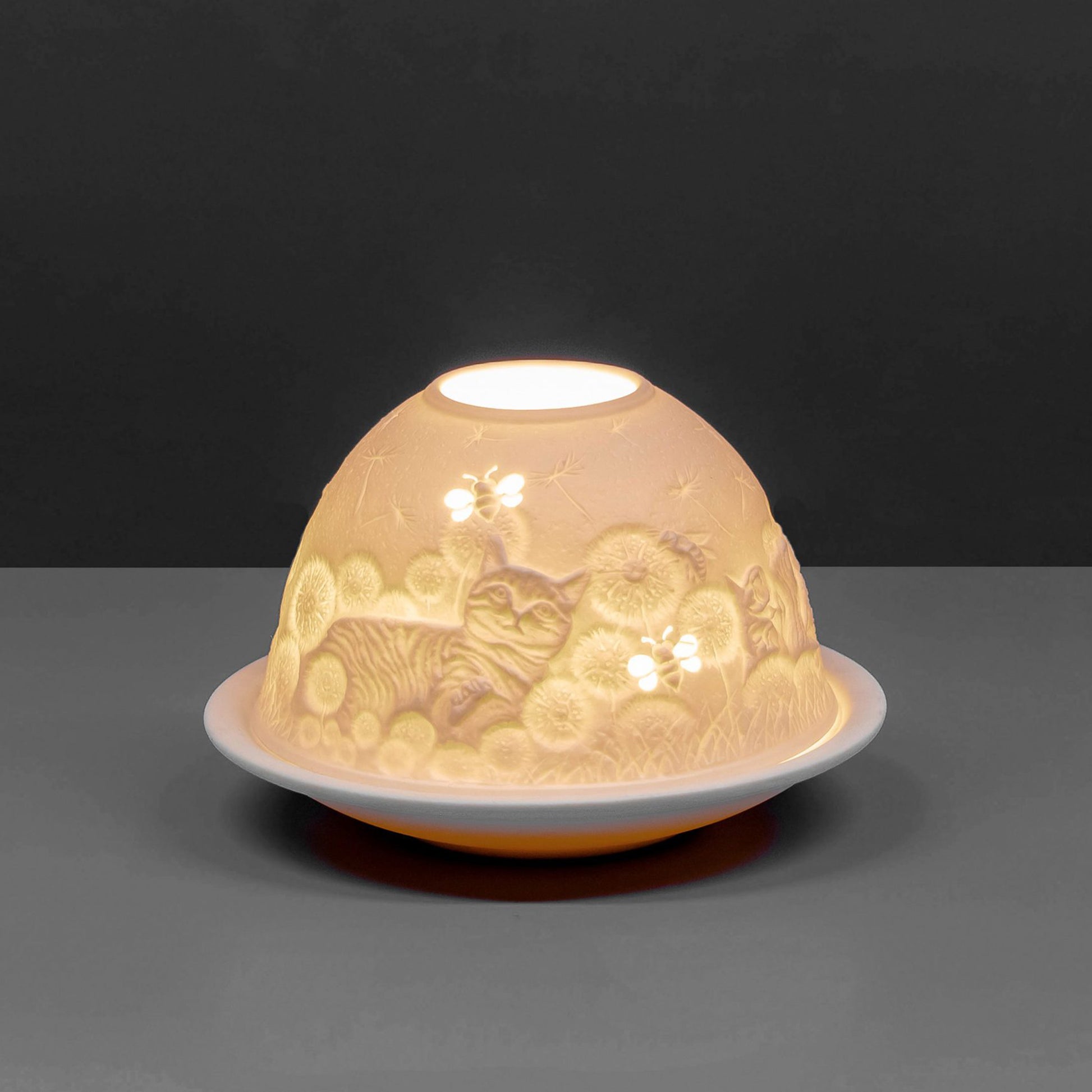 White porcelain tall dome candle holder with engraved cat and bees design lit up