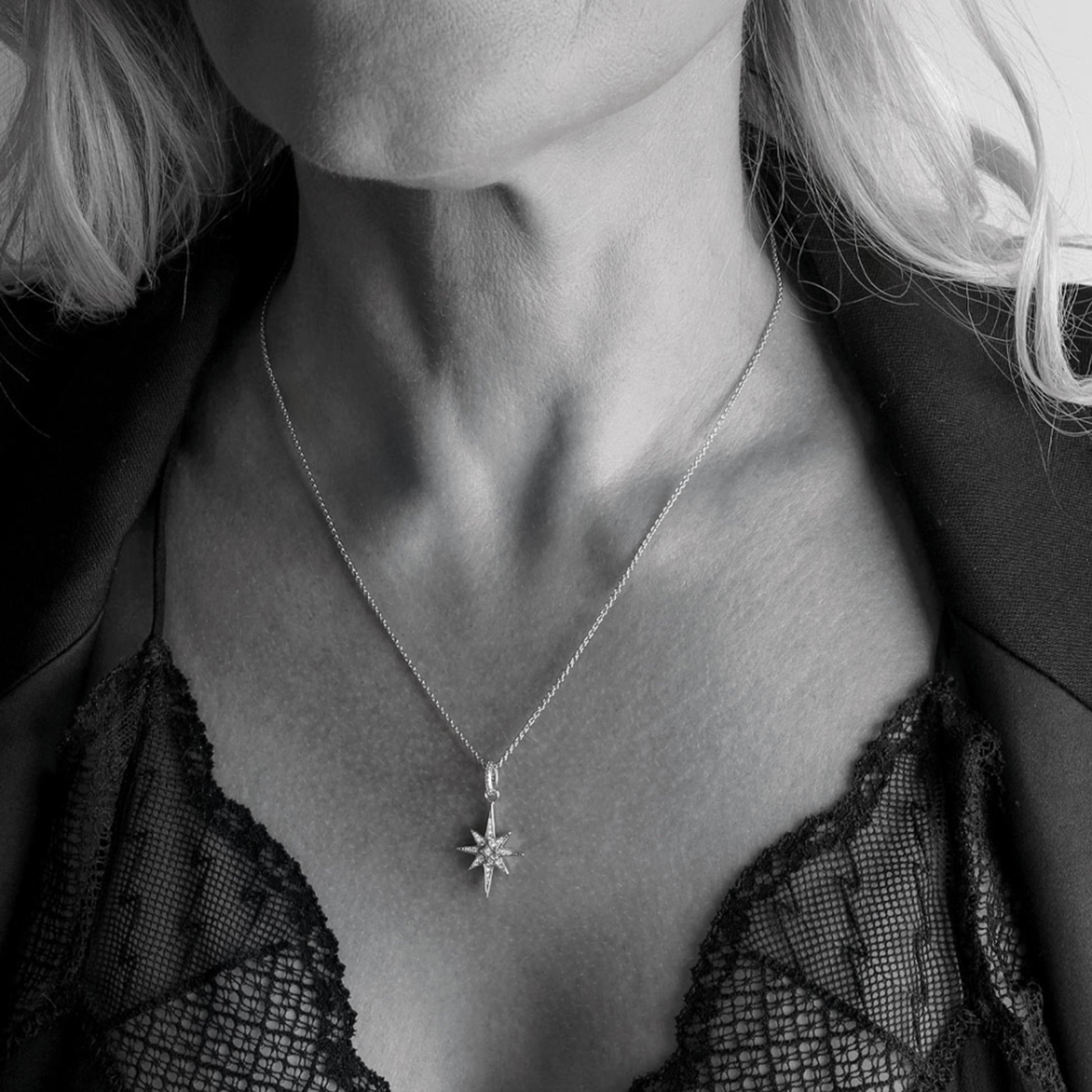 Model wearing a small silver North star shaped pendant with cubic zirconia stones