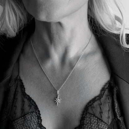 Model wearing a small silver North star shaped pendant with cubic zirconia stones