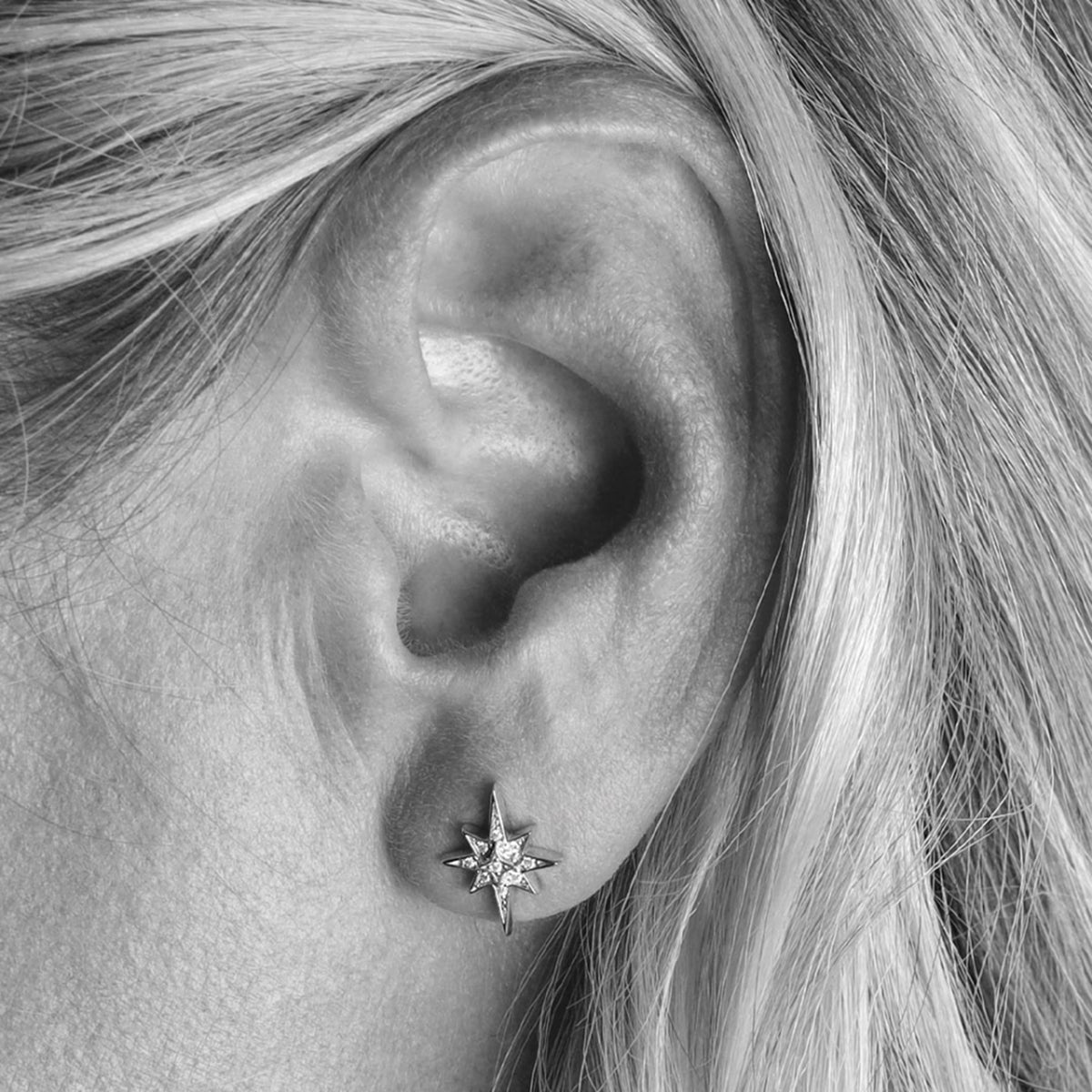 A model wearing a pair of silver star shaped stud earrings with CZ stones