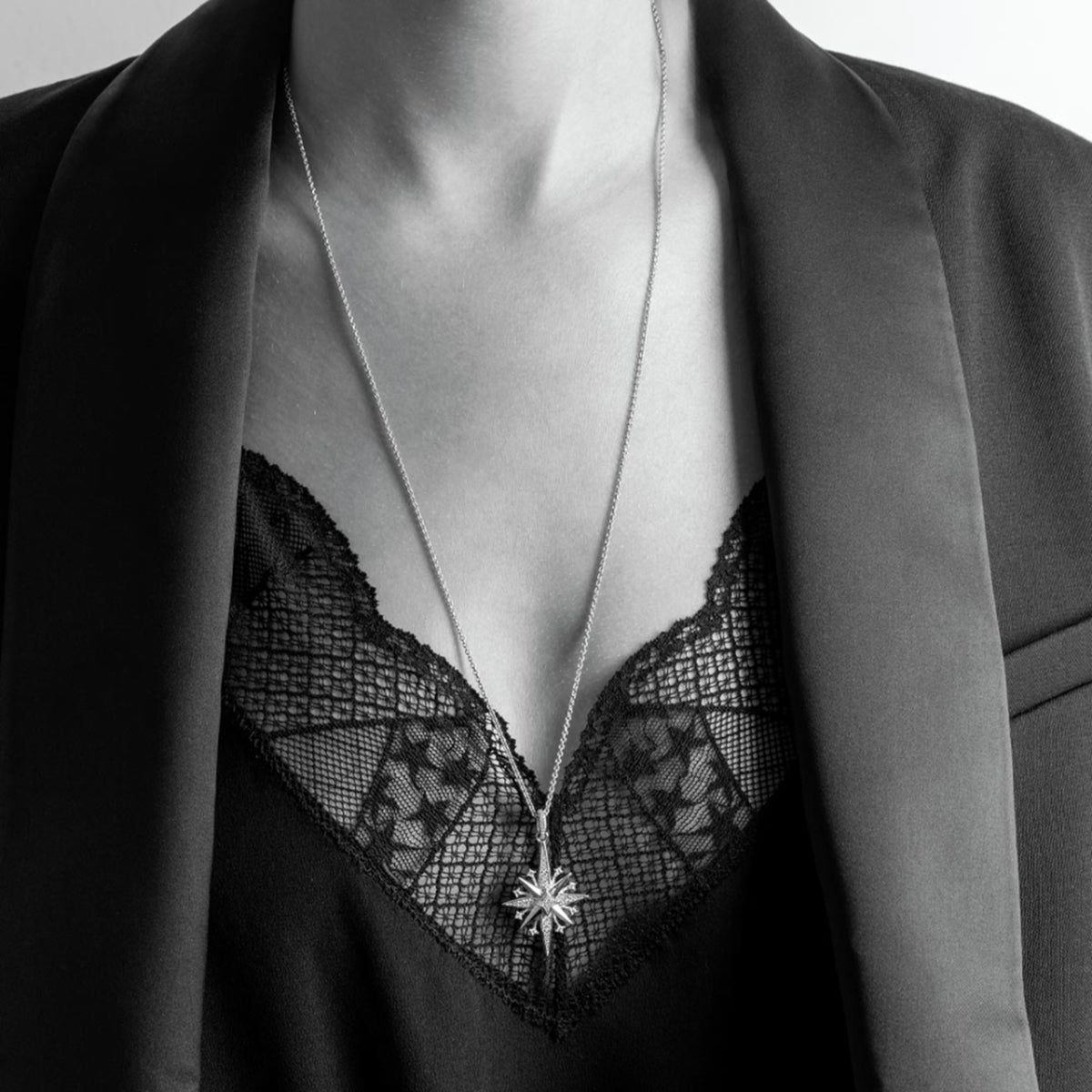 Model wearing a silver North star shaped pendant with cubic zirconia stones and long silver chain