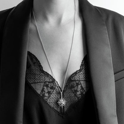 Model wearing a silver North star shaped pendant with cubic zirconia stones and long silver chain