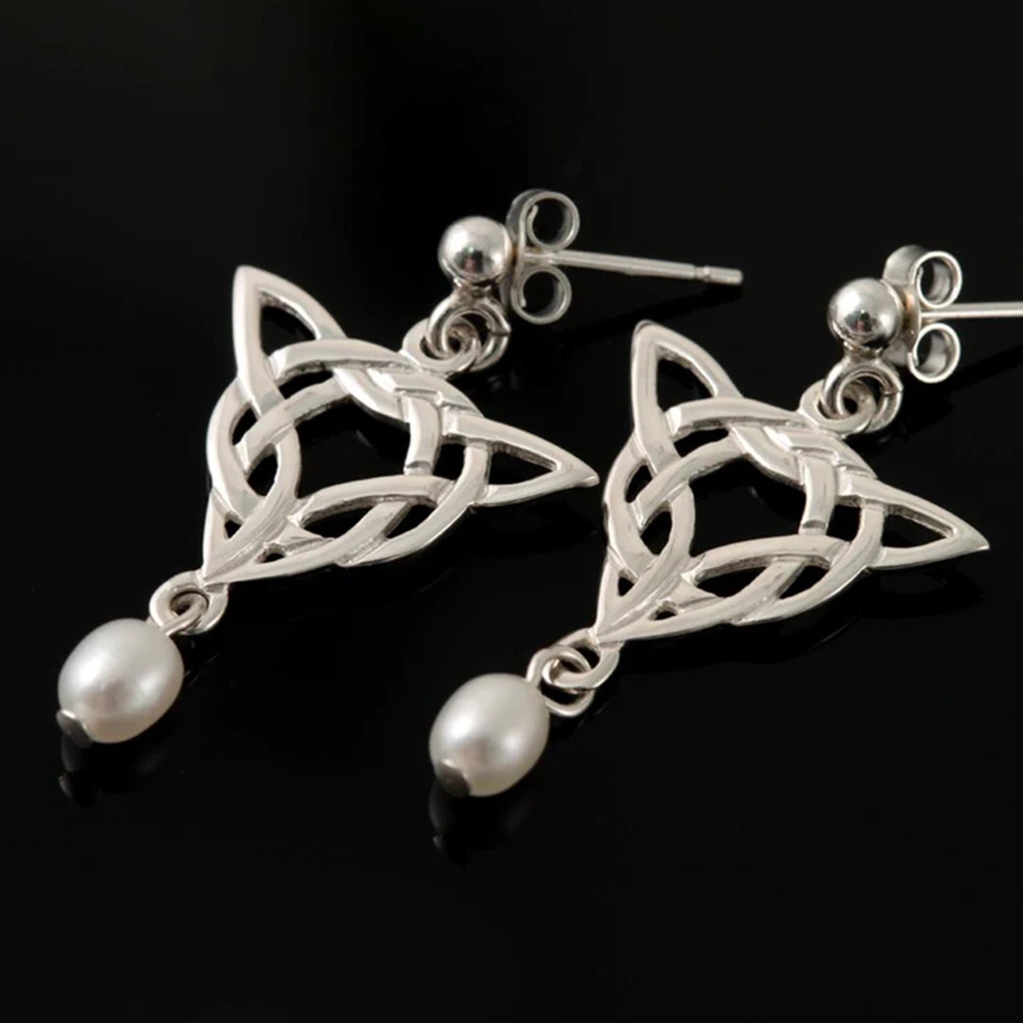 A pair of silver trinity knot style drop earrings with teardrop shaped dangling white pearls